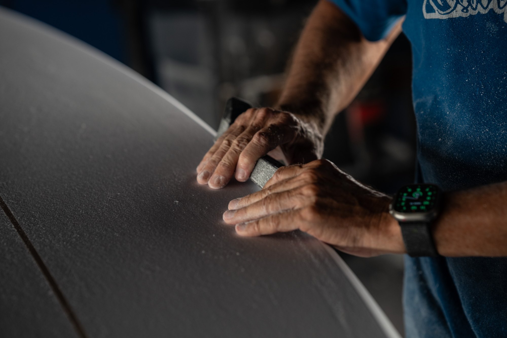 Mike Whisnant's hands working the rail of a board with a sanding block
