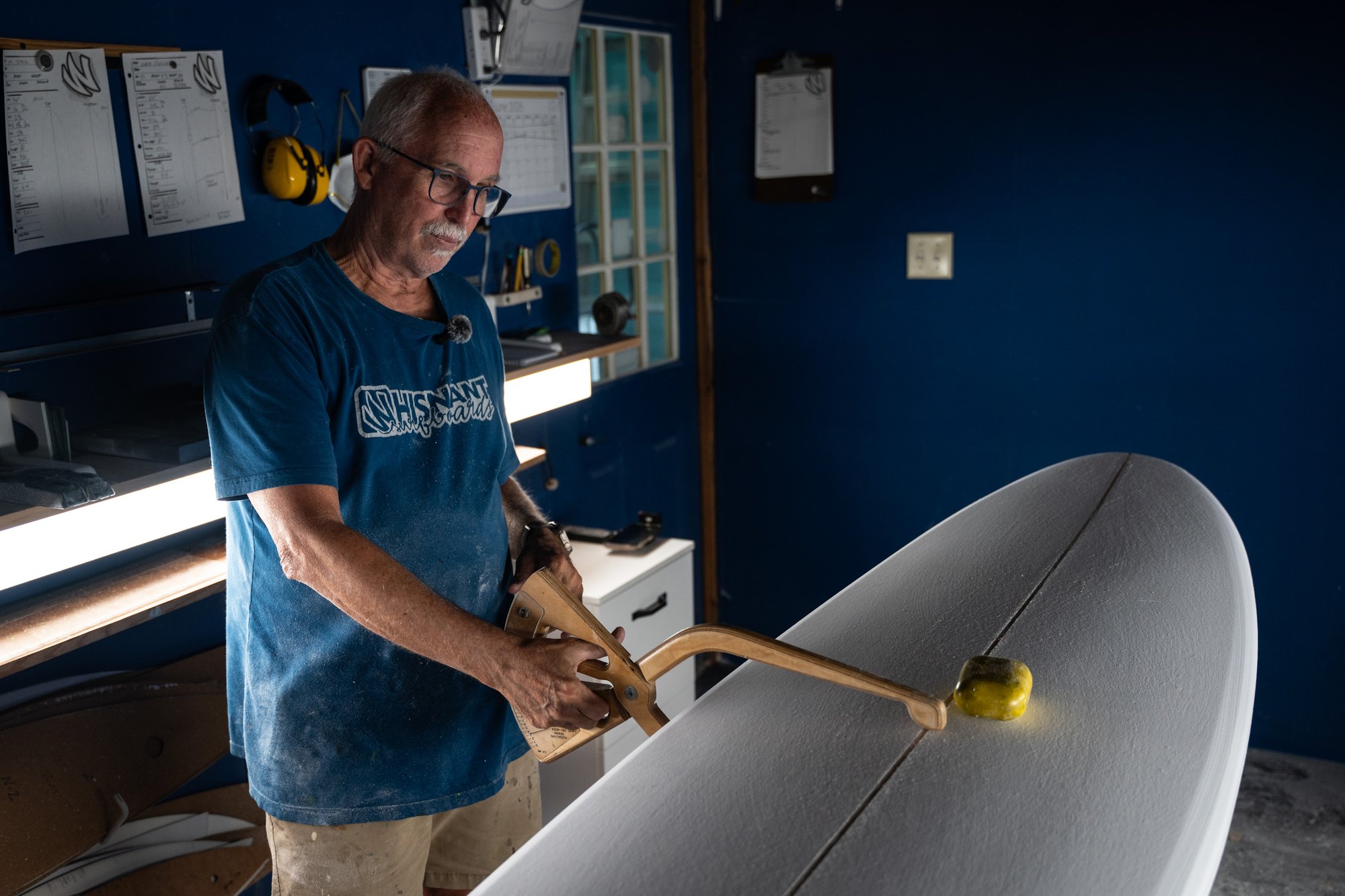 Mike Whisnant holding a wooden caliper to the rail of a board, checking its dimensions