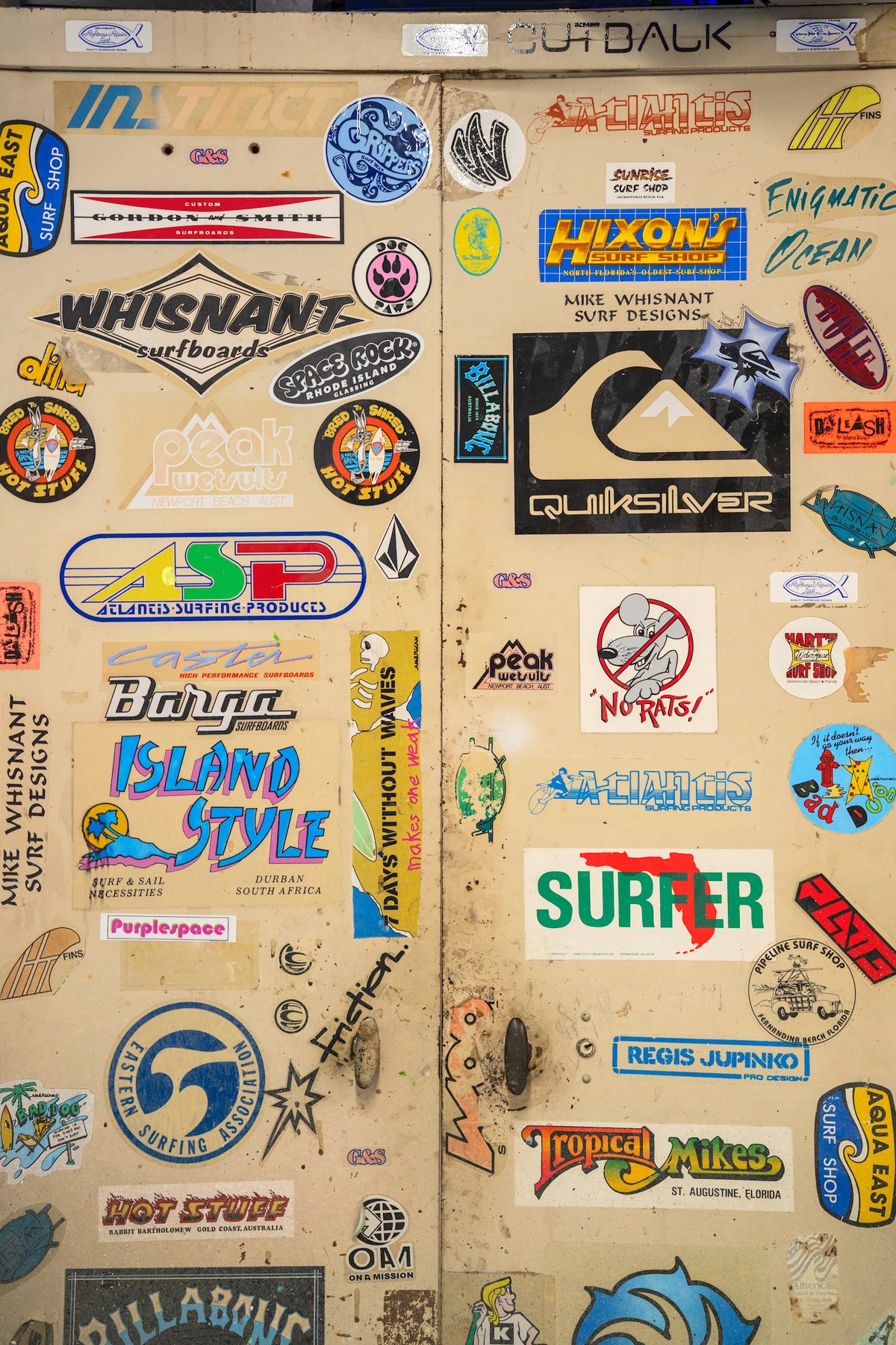 The sticker-covered cabinet doors in Mike Whisnant's glassing room, layered with decades of surf-industry decals