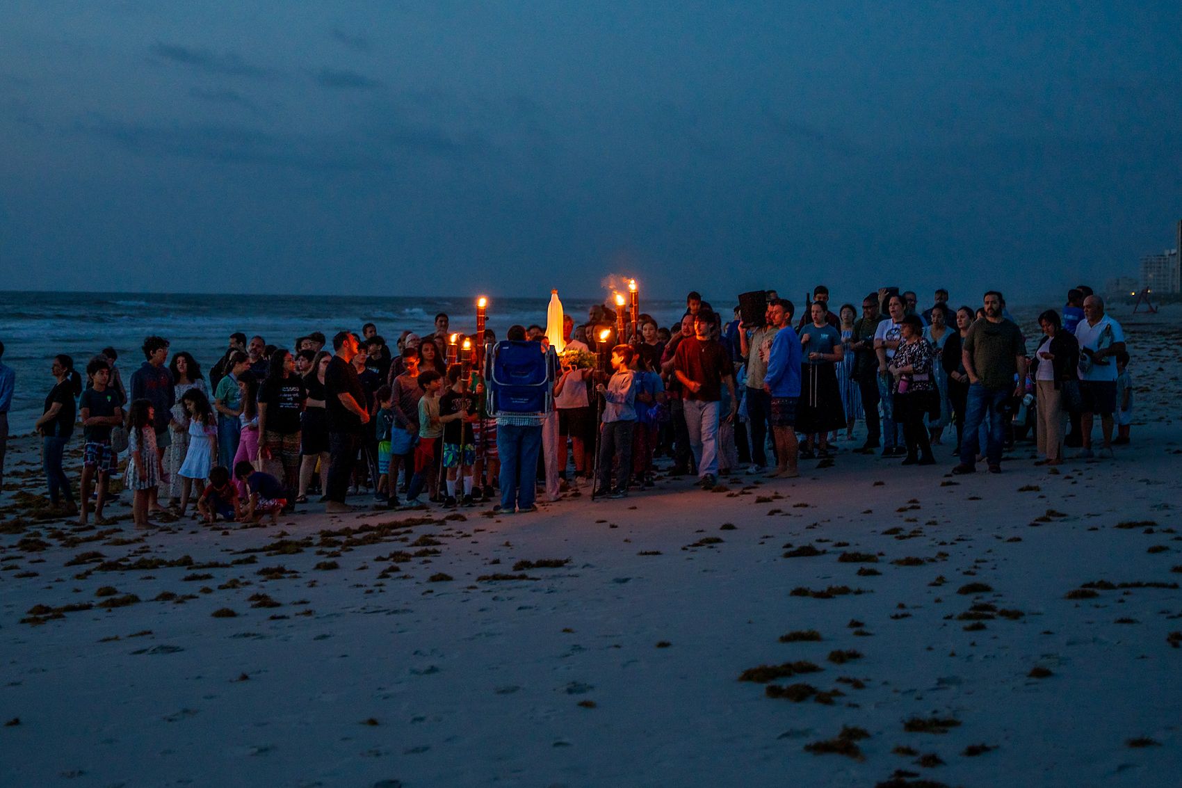 A group gathered on the beach to pray the rosary