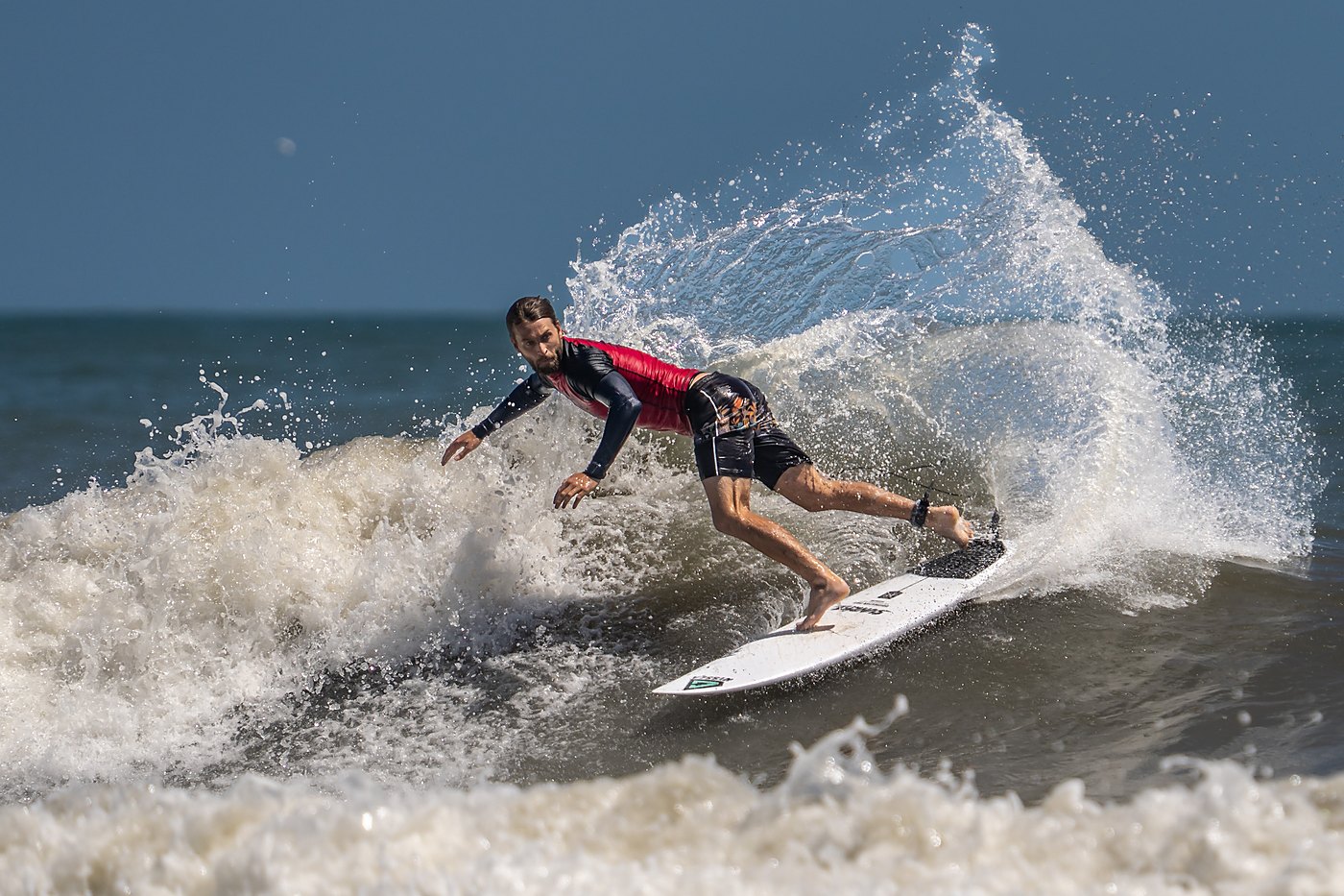 Surfer carving and sending up a tall fan of whitewater