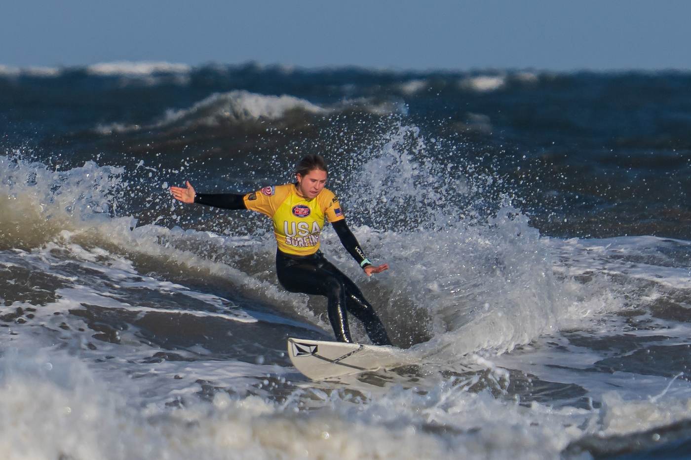 Lanea Mons backside carve, yellow USA Surfing jersey