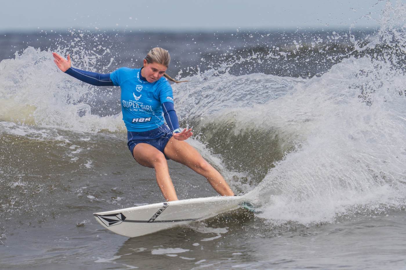 Female surfer in a competition jersey carving on a wave