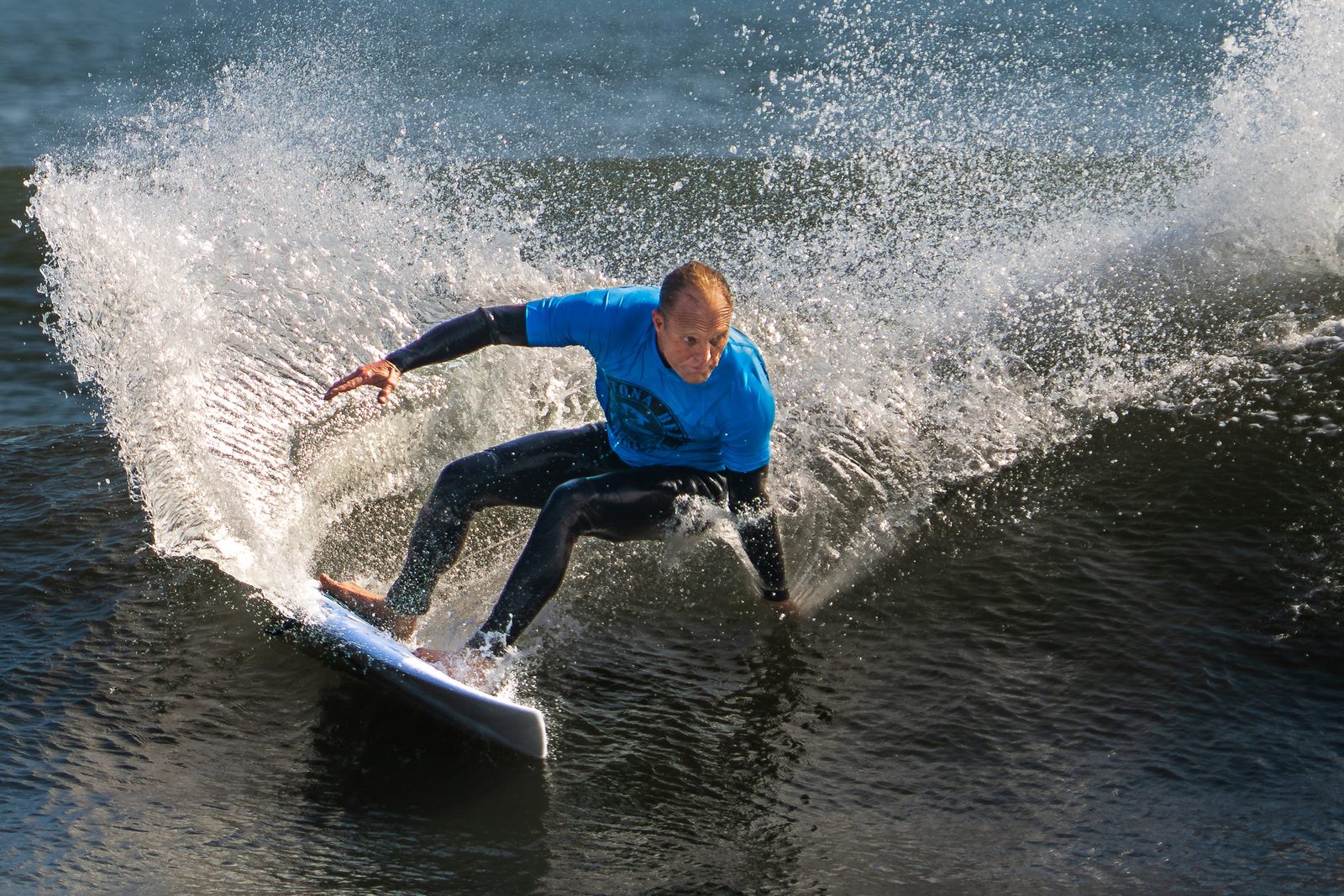 Surfer carving a backlit cutback with the sun behind the spray