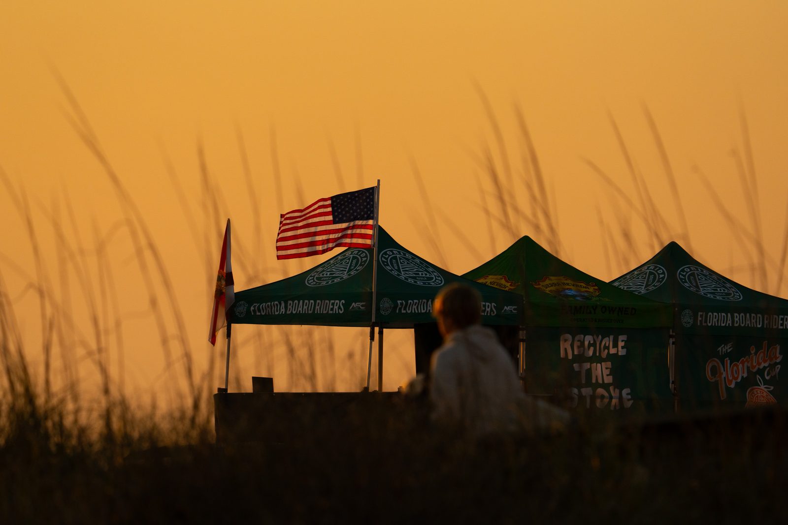 Florida Board Riders contest tents with U.S. and Florida flags at dawn