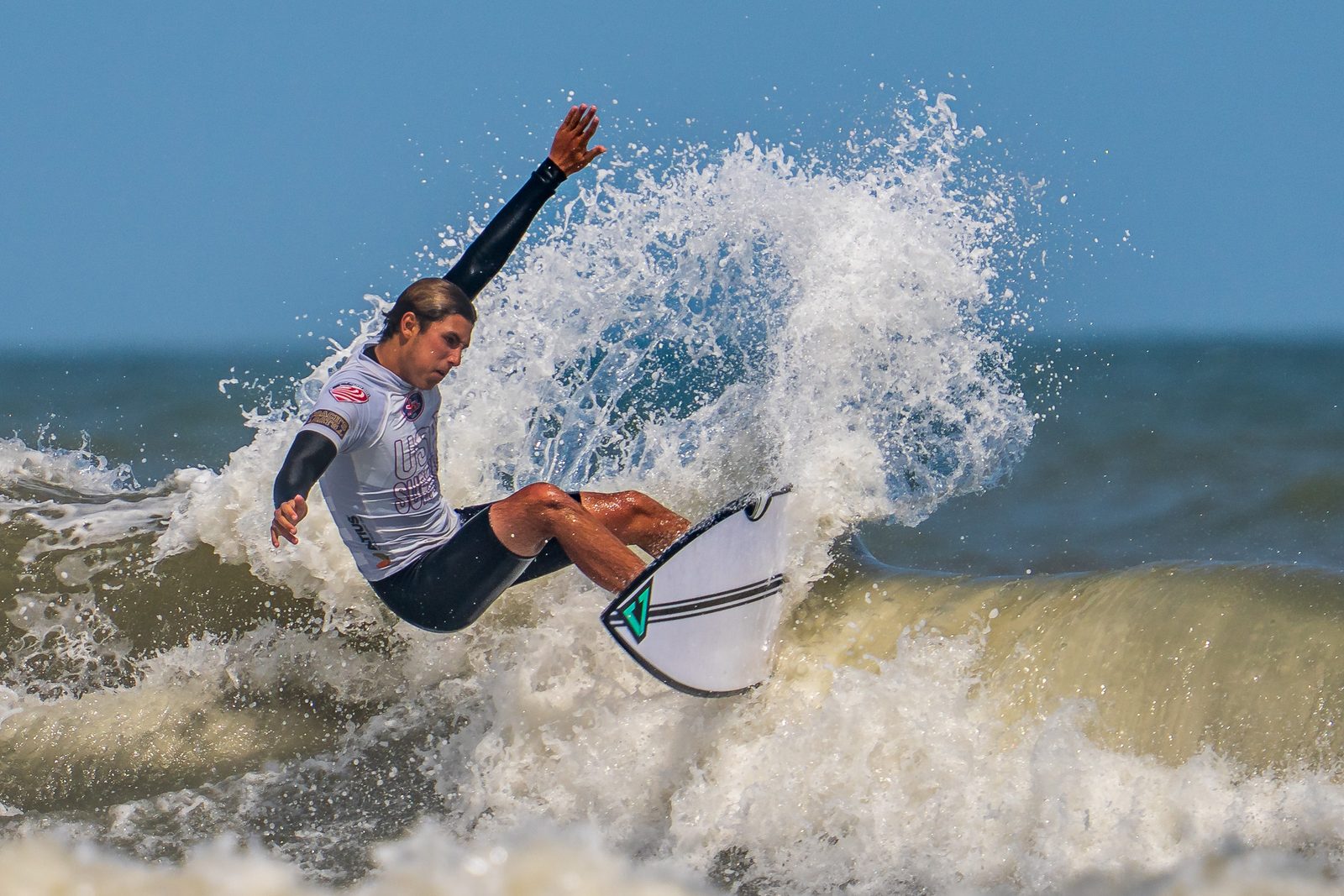 Surfer driving hard off the top with one arm extended