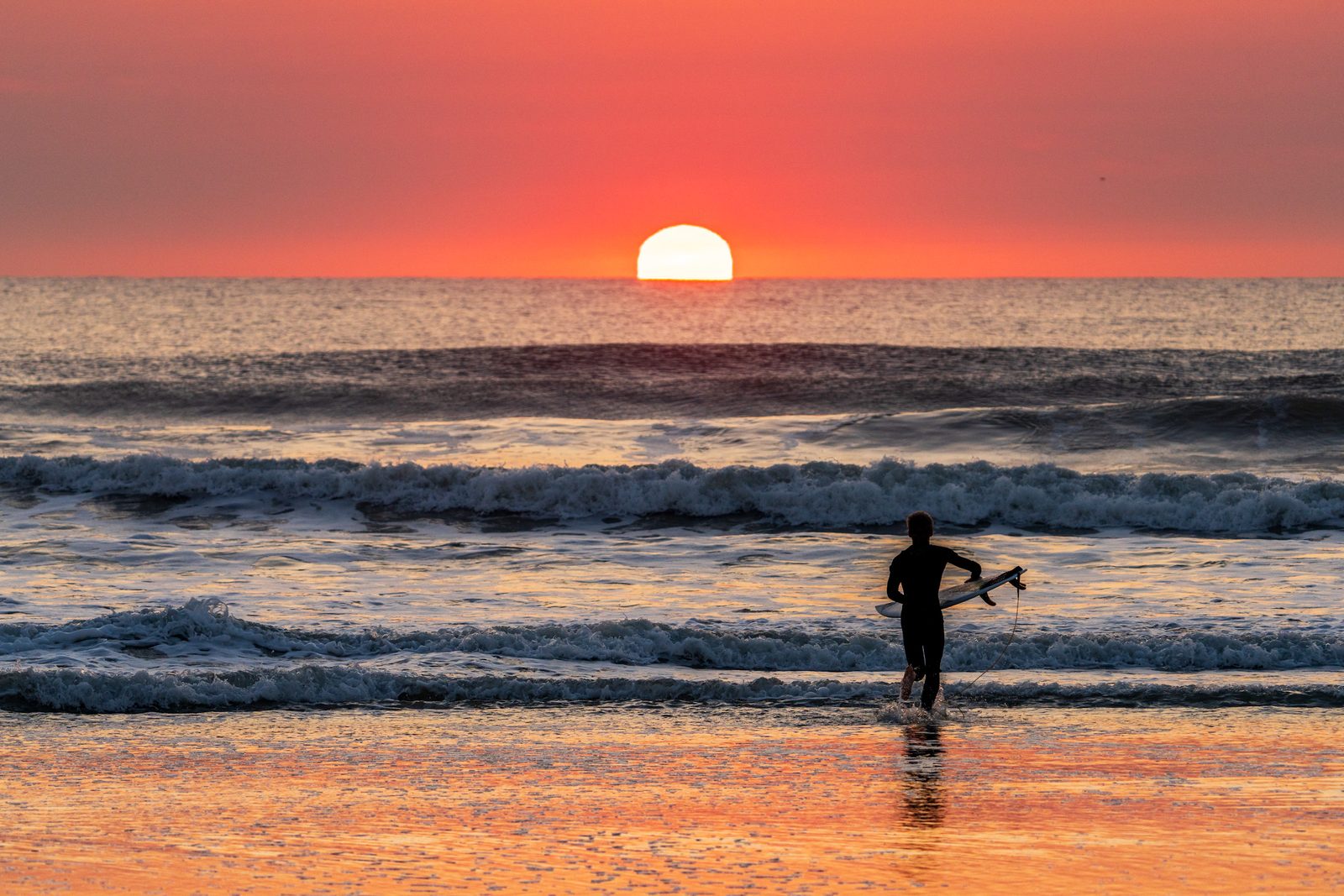 A surfer walks into the water at first light on Florida's First Coast