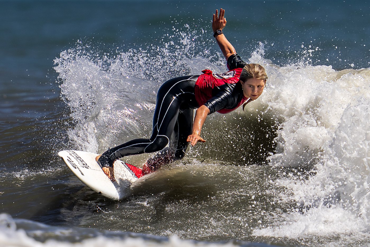 Surfer in a bottom turn with fingertips on the water