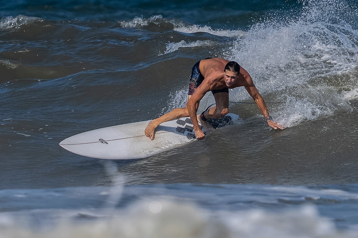 Longboarder dragging a hand along the wave face