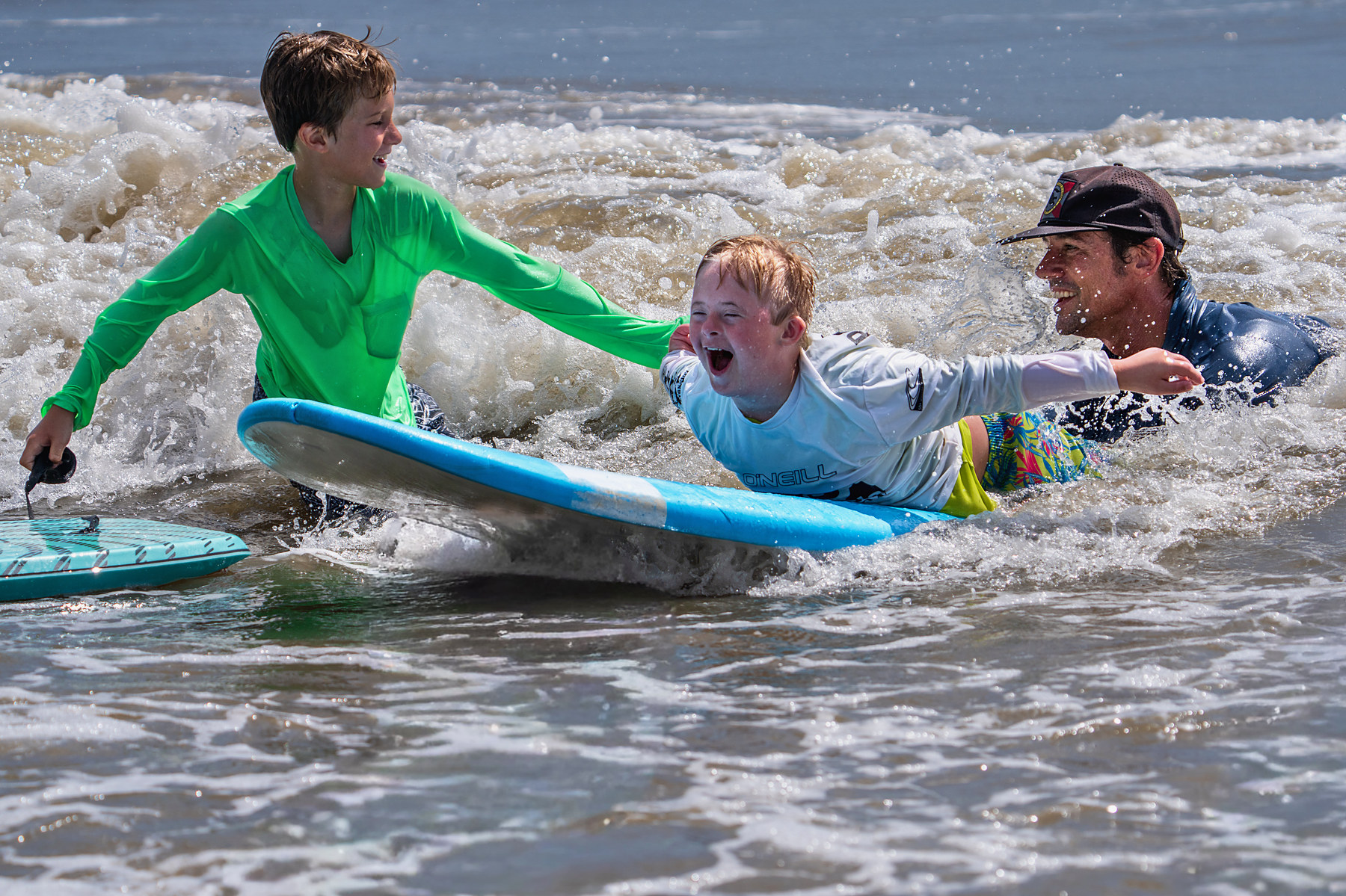 A brother alongside, a volunteer pushing from behind, and a wave that went the whole way to the sand.