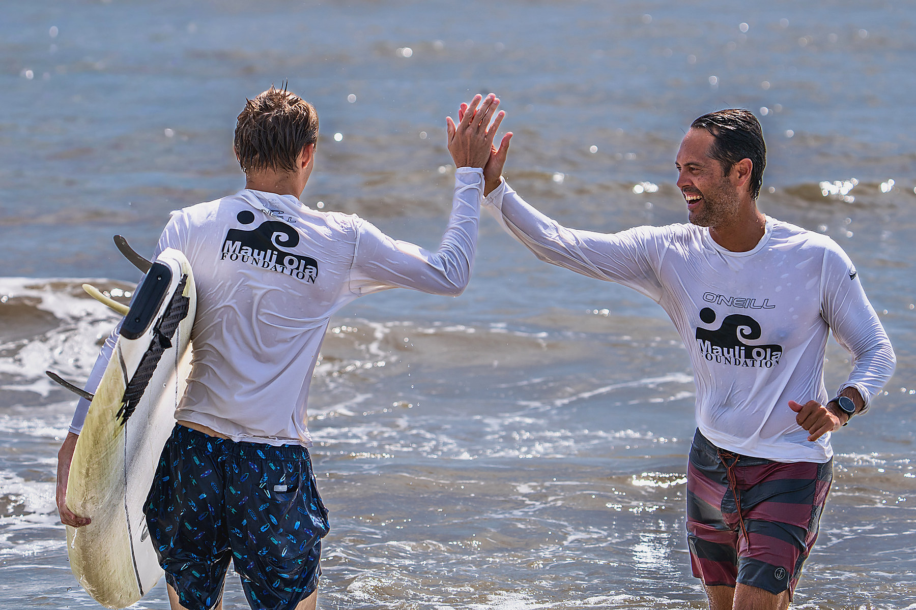 He walks his own board in and trades a high five with the volunteer who spent the morning alongside him. By this point they are wearing the same shirt.