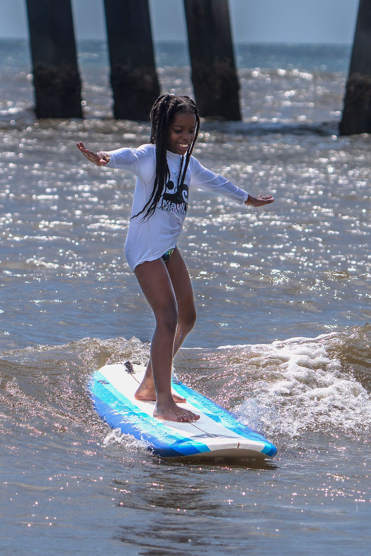 The same surfer a moment later, arms wide, riding the wave in on her own.