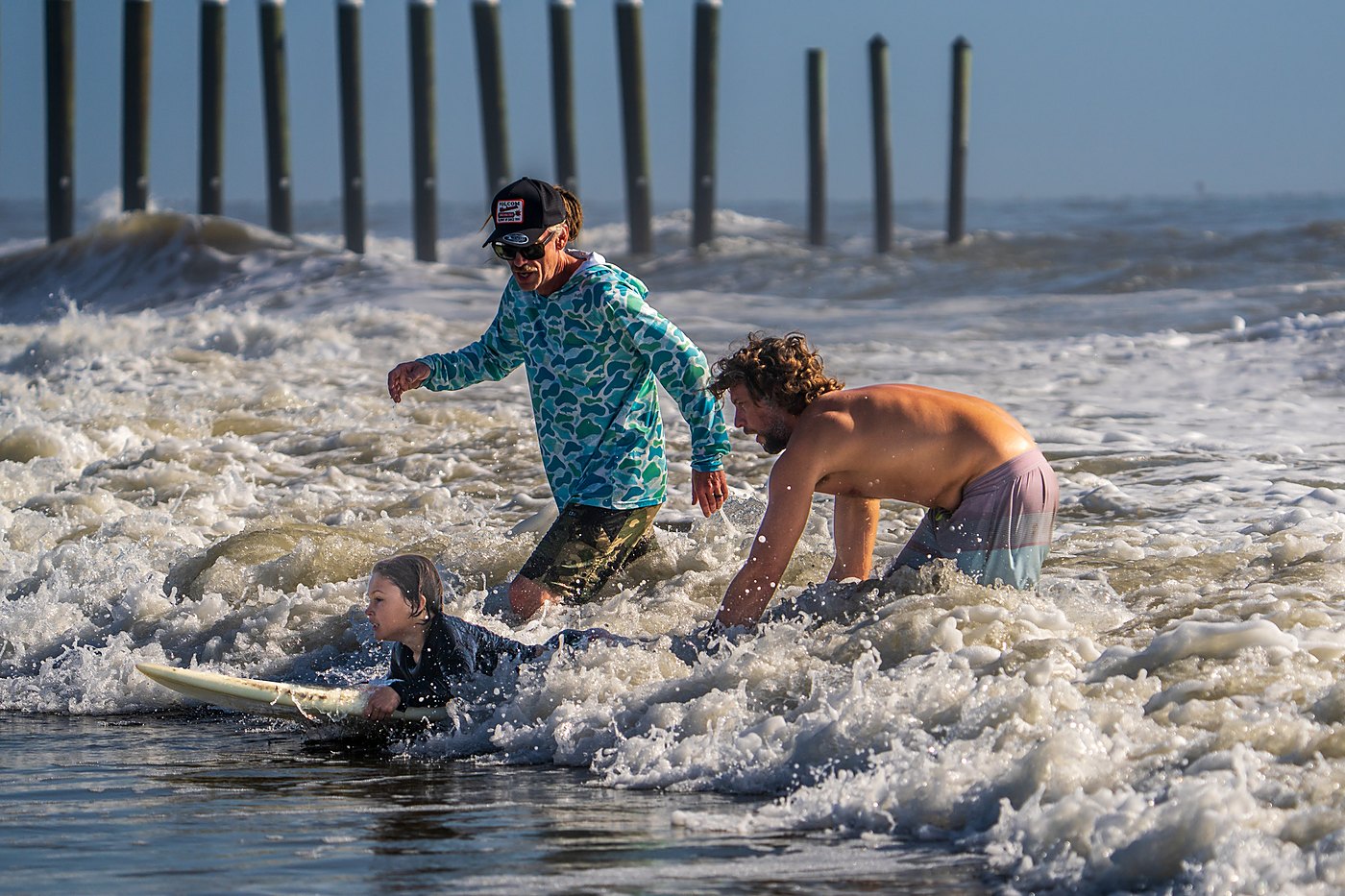 Surf instructor helping a young rider catch a small wave