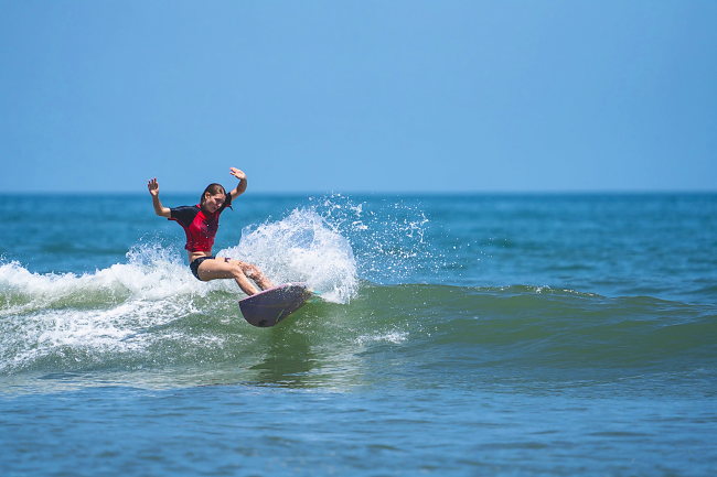 A young competitor in a red jersey turns on a small inside wave.