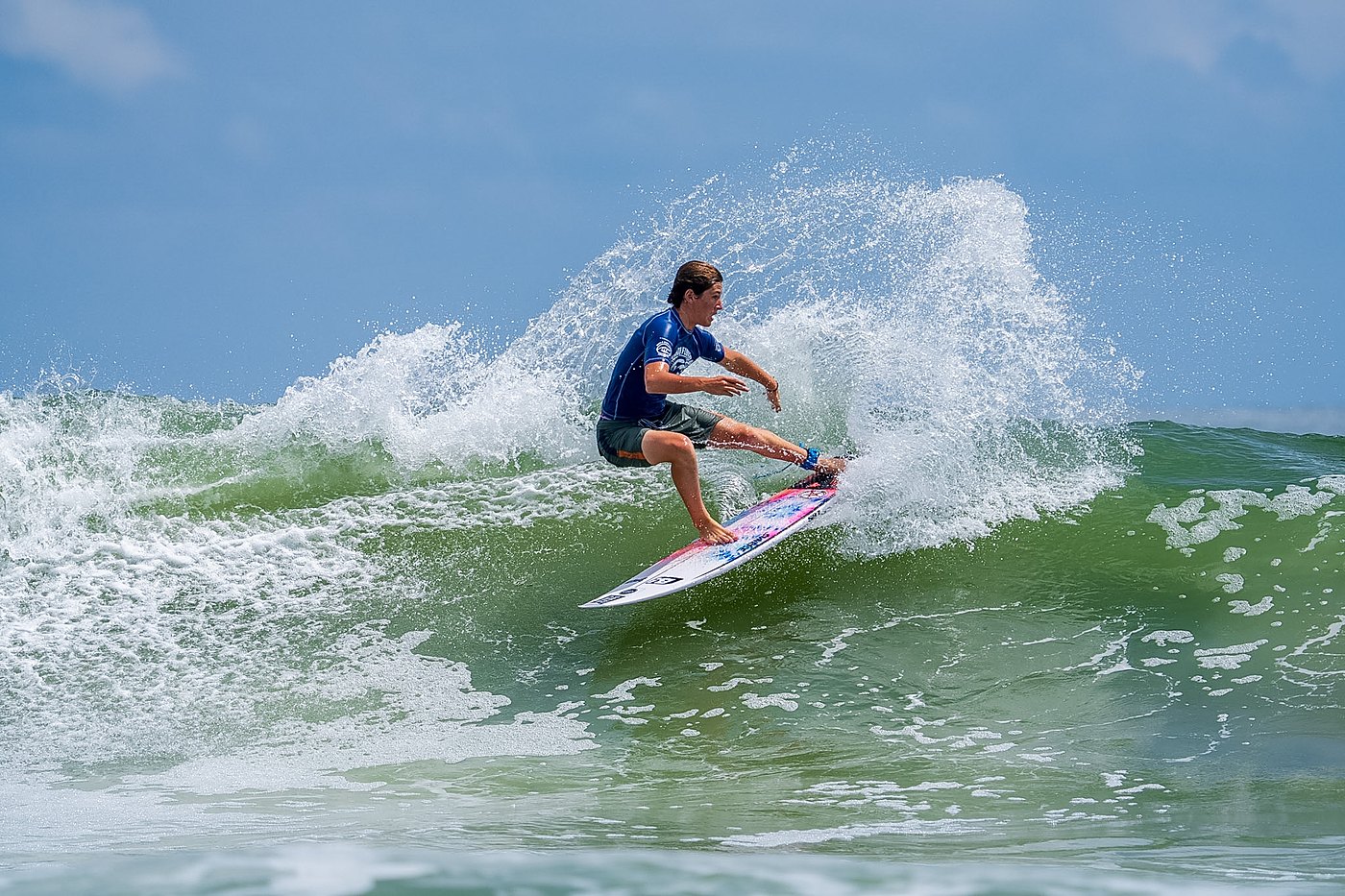 Surfer top turn throwing a fan of spray against the sky