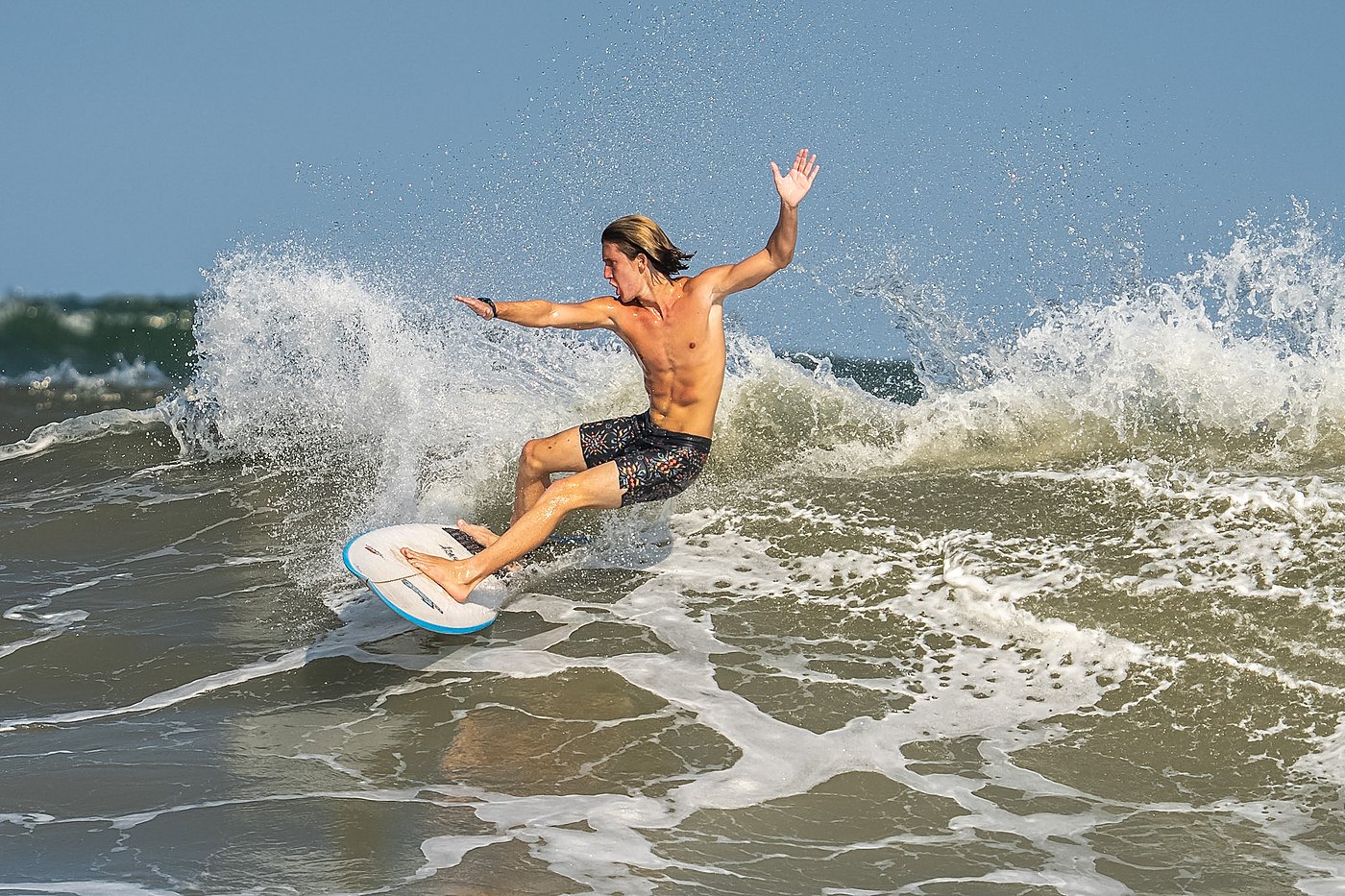 Surfer leaning into a bottom turn with arms wide
