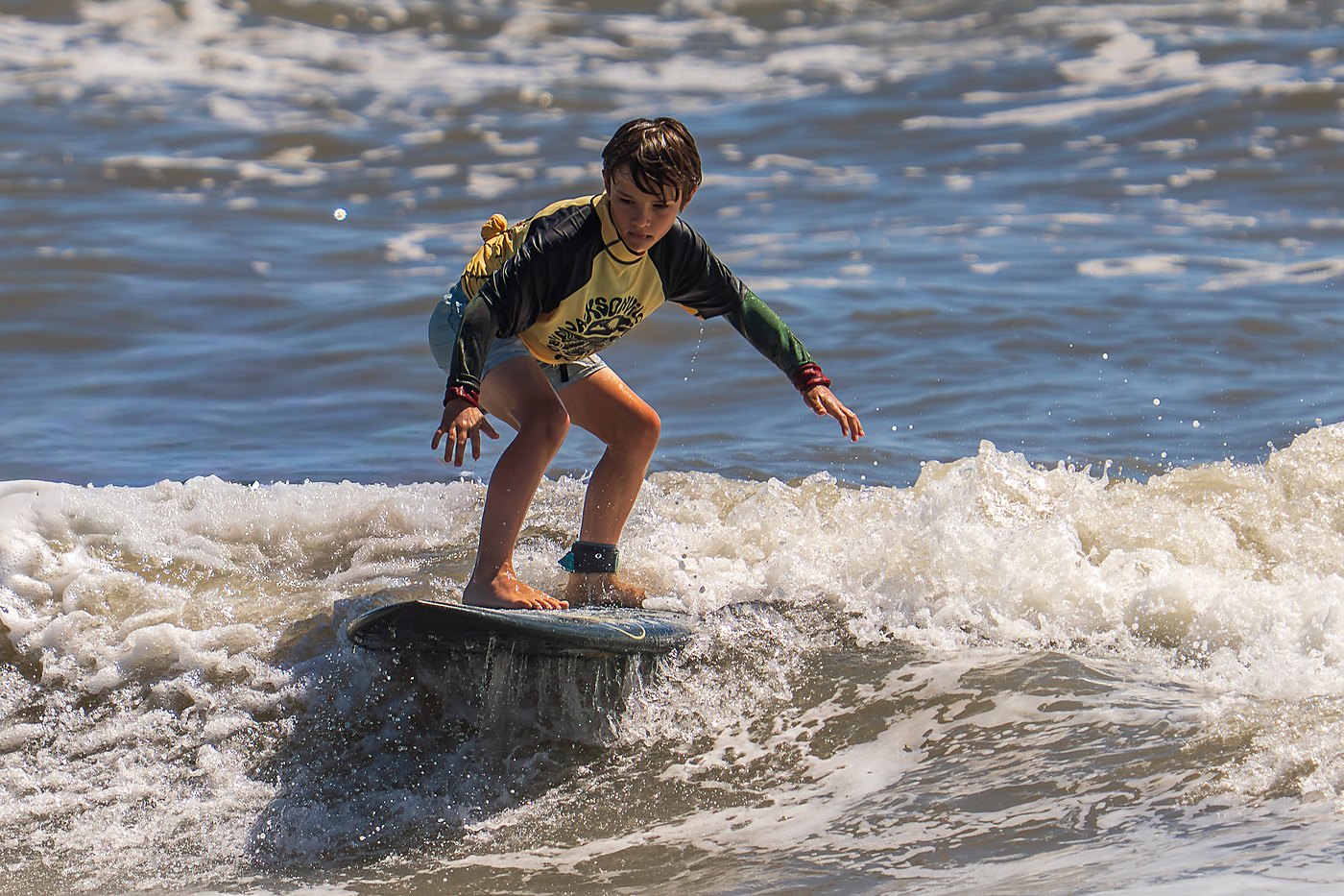 Young surfer riding a small wave toward the beach